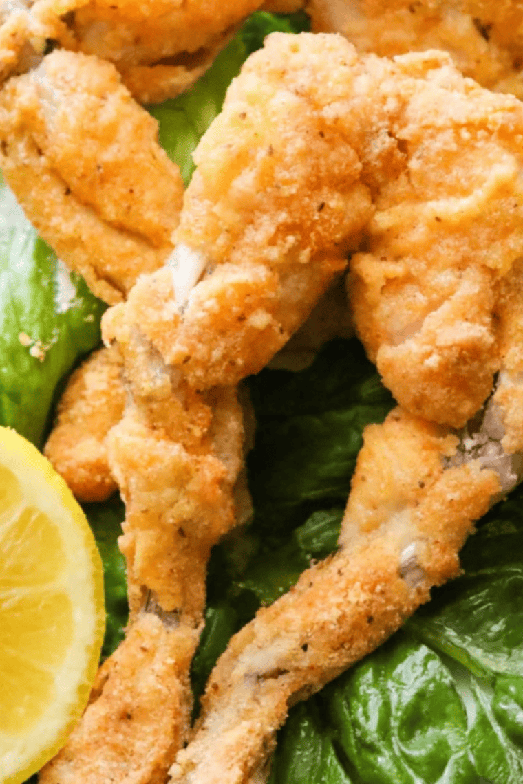 Golden, crispy air fryer frog legs served on a plate with fresh herbs.