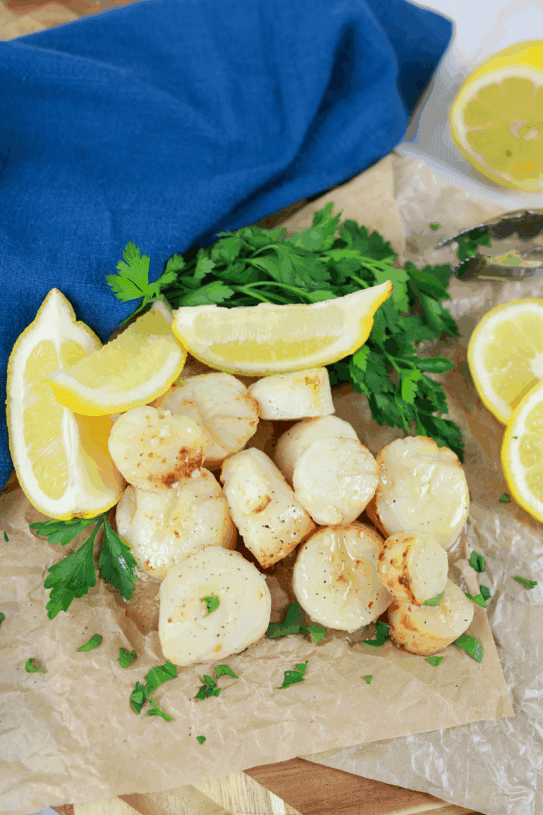 Golden, perfectly cooked garlic butter scallops served on a plate with fresh herbs.