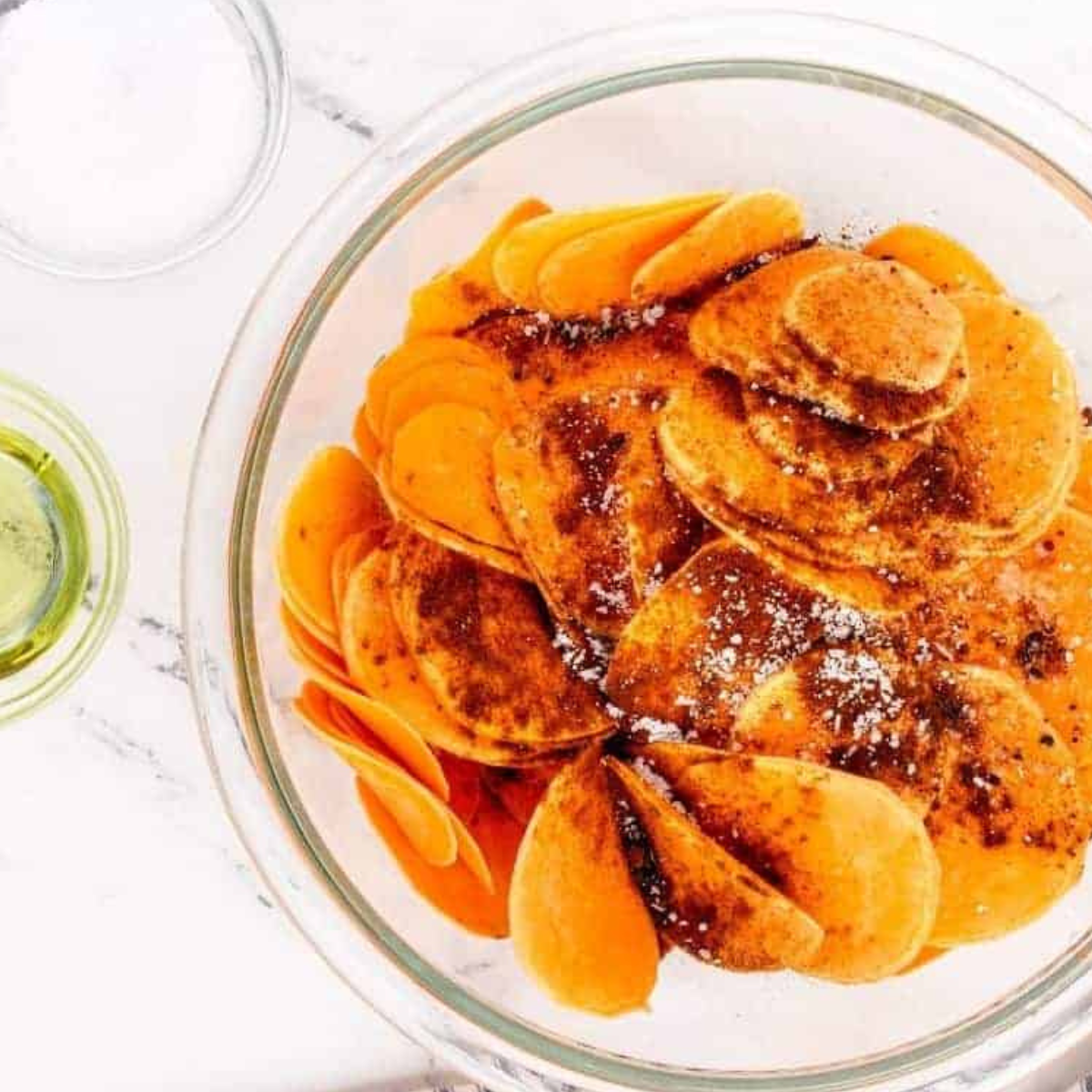 Coating sweet potato slices with seasoning before air frying.