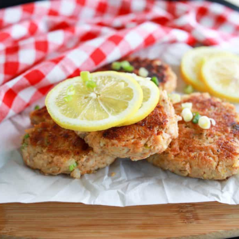 Finished griddle crab cakes garnished with herbs and lemon, ready to serve
