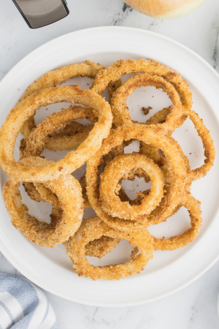 Onion rings sizzling on a Blackstone flat top griddle with light oil