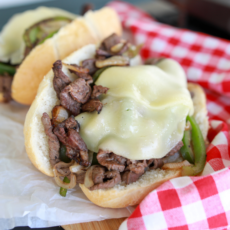 Close-up of a cheesy Blackstone Philly Cheesesteak made with tender ribeye steak and caramelized onions.