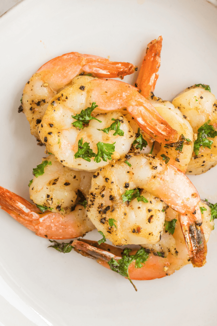 Crispy golden air fryer shrimp coated with garlic, parmesan, and fresh parsley on a plate.