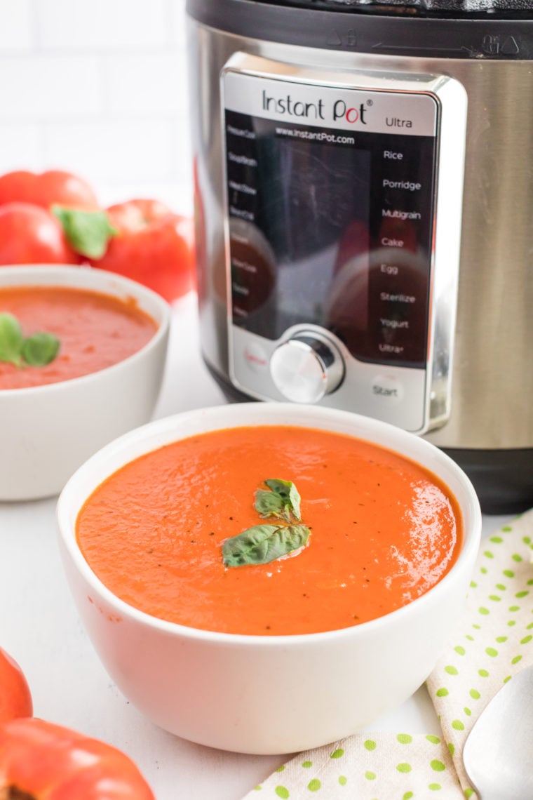 Serving a bowl of Instant Pot Copycat Campbell’s Tomato Soup with a side of crusty bread.