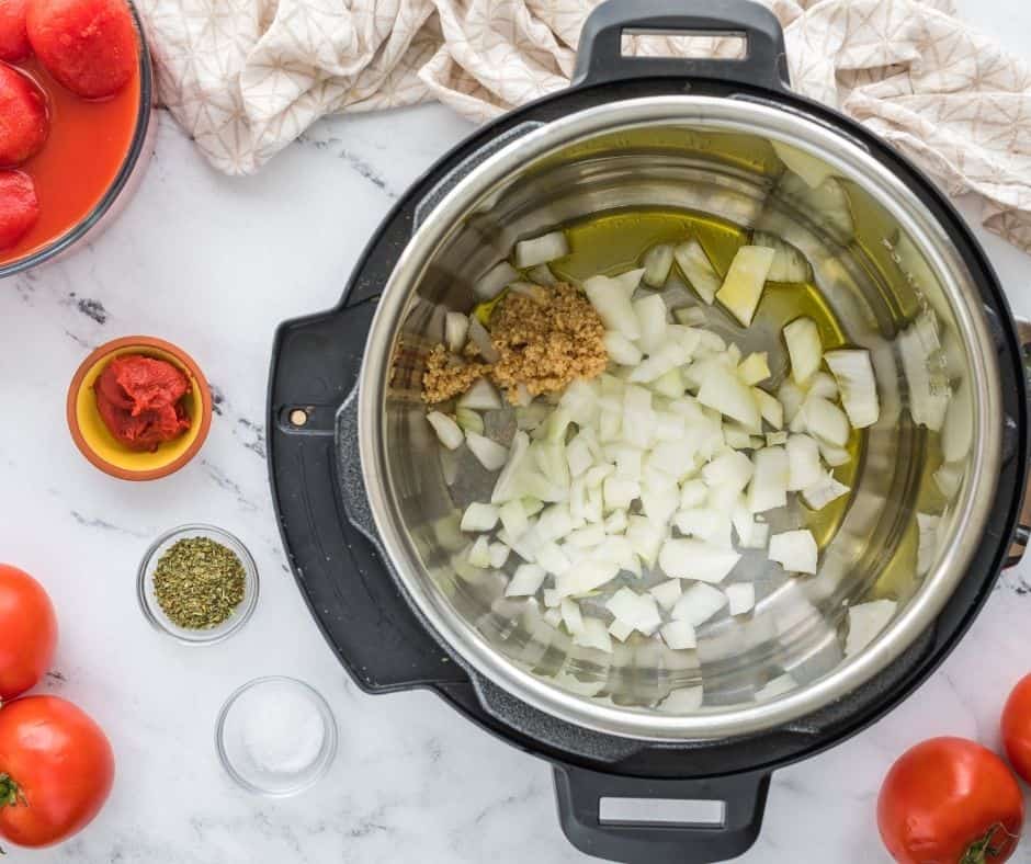 "Adding diced tomatoes, onions, and garlic to the Instant Pot for making tomato soup."
