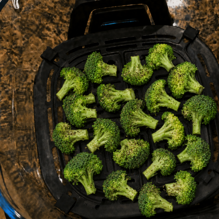 Air-fried broccoli florets in a Ninja Crispi glass container.