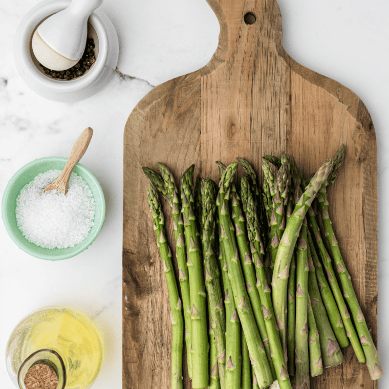 Fresh asparagus being washed, trimmed, and patted dry with a paper towel.