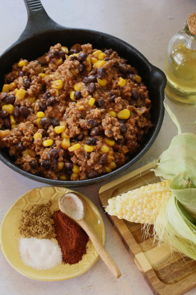 Heat oil over medium-high heat in a medium oven-proof skillet. Add onion and cook for 3-4 minutes or until golden brown. Add ground beef, chili powder, and salt. Cook for 5-8 minutes until meat is brown and no longer pink. Stir in tomato sauce, black beans, and corn. Bring to a boil and simmer for 8-10 minutes. Reserve.