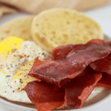 strips of bacon next to a fried egg in a ramekin