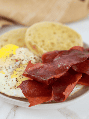strips of bacon next to a fried egg in a ramekin
