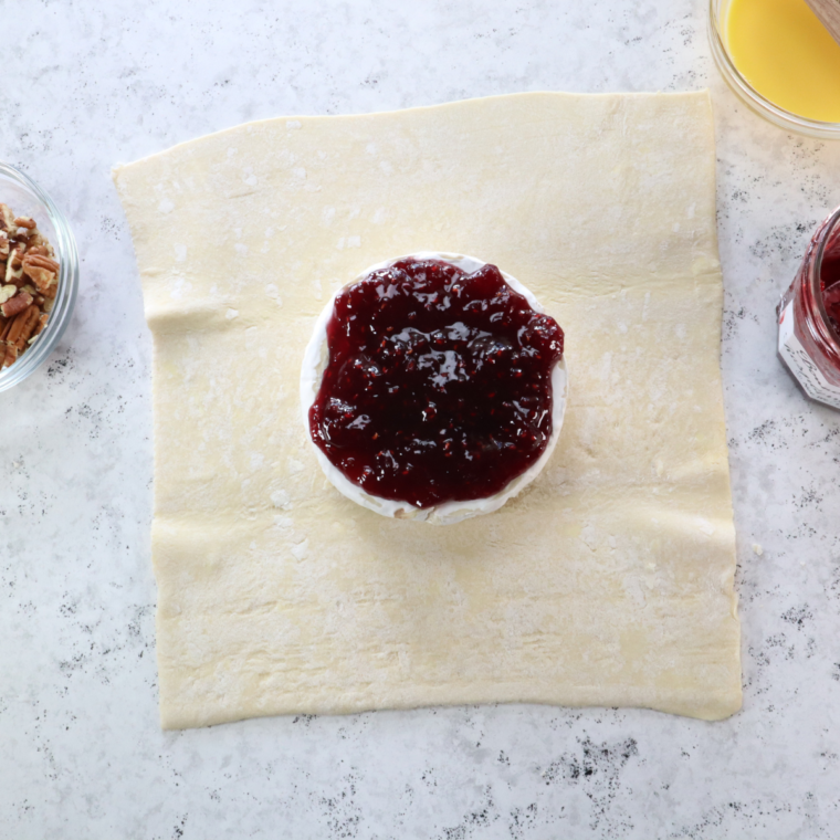 Prep the Brie (If Using Puff Pastry):
Roll out the sheet of puff pastry dough on a lightly floured surface if you're using puff pastry.
Place the Brie in the center of the pastry.
Add your chosen toppings on top of the puff pastry.
Fold the pastry over the Brie, completely encasing the cheese, and trim any excess pastry. Seal the edges.
Whisk the egg and brush it over the pastry with a pastry brush for a golden finish.