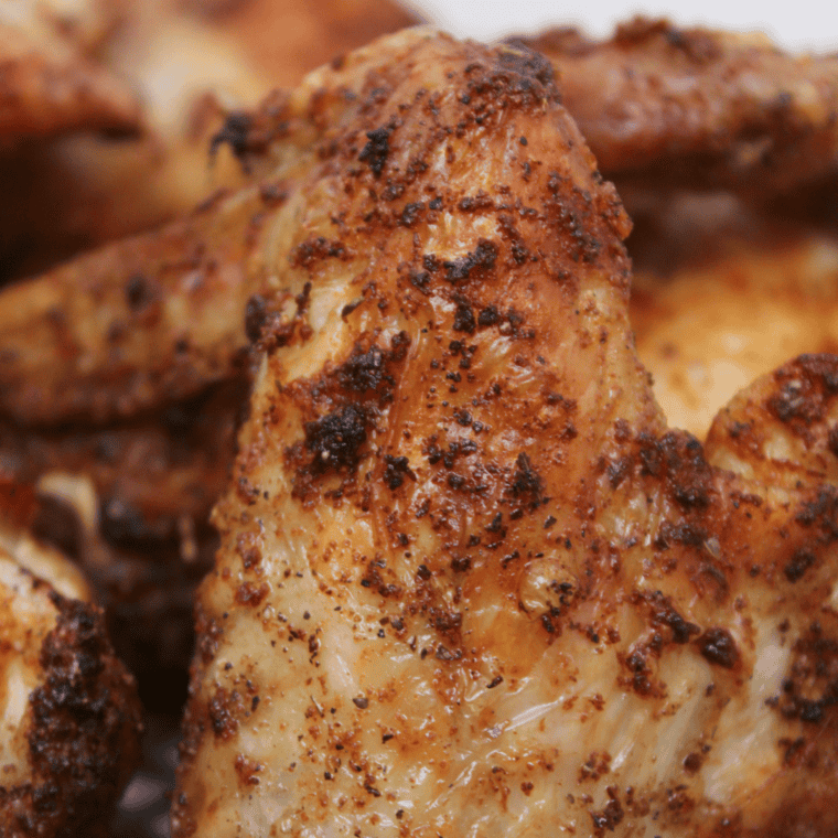 Air fryer basket with seasoned dry rubbed chicken wings"