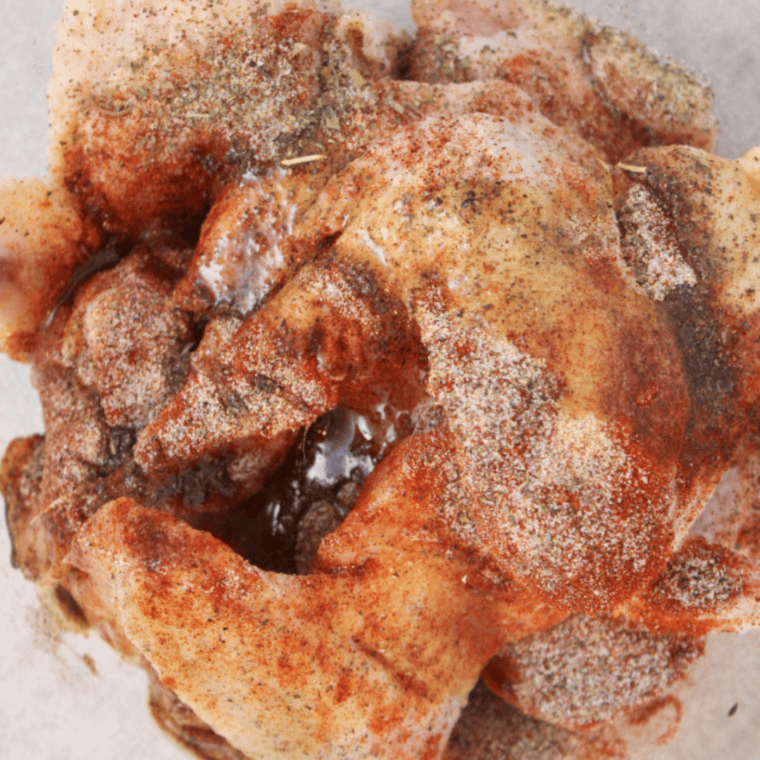 Seasoning chicken wings with dry rub in a mixing bowl