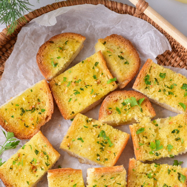 Close-up of air fryer garlic bread slices with toasted edges and visible herbs like parsley and basil.
