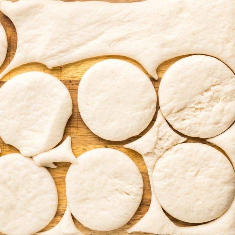 Rolling out and cutting pizza dough for easy assembly.