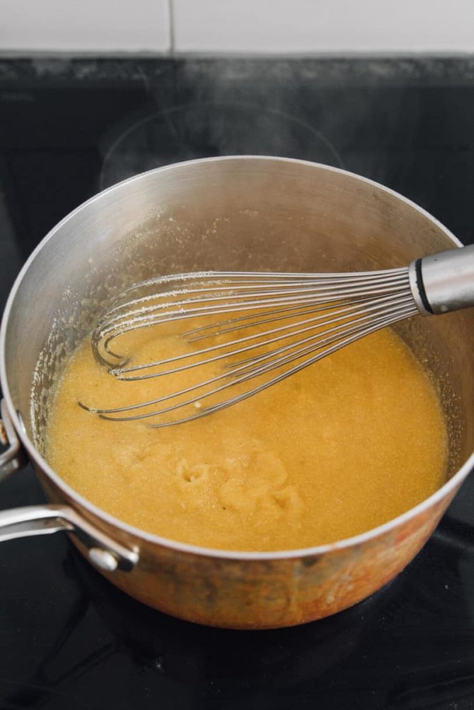 Whisking instant polenta into simmering vegetable broth