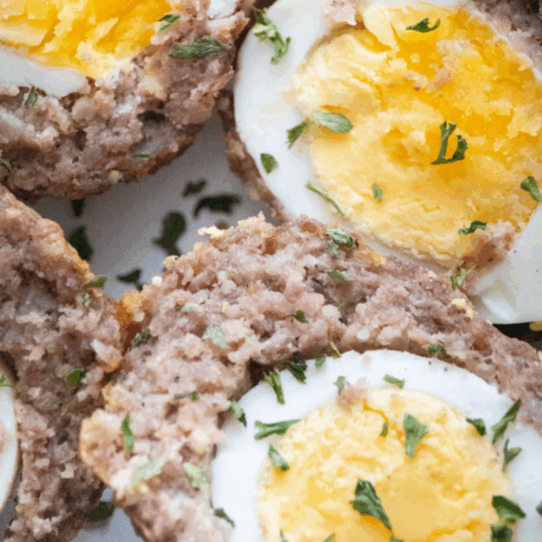 Air fryer Scotch eggs on a plate, golden and crispy with cooked sausage and egg center