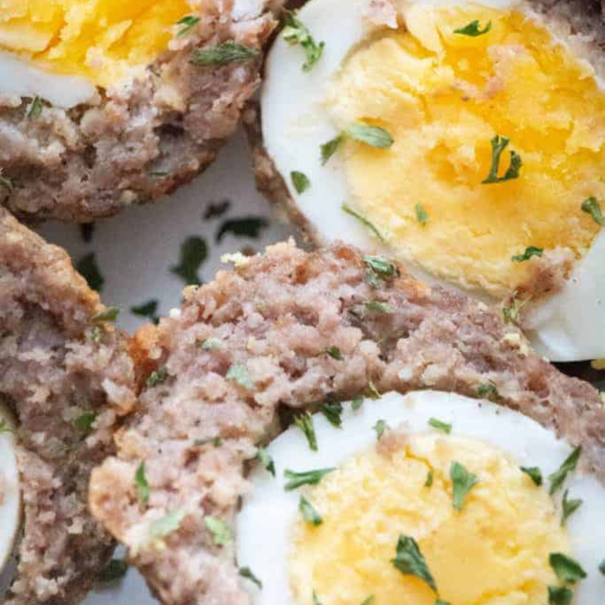 Cooked Scotch eggs cooling slightly on a plate, ready to serve with dipping sauce