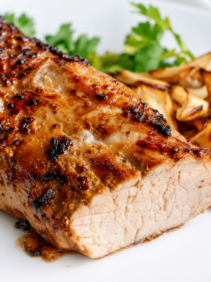 Air fryer teriyaki pork tenderloin with a glossy glaze and roasted onions on a white plate.