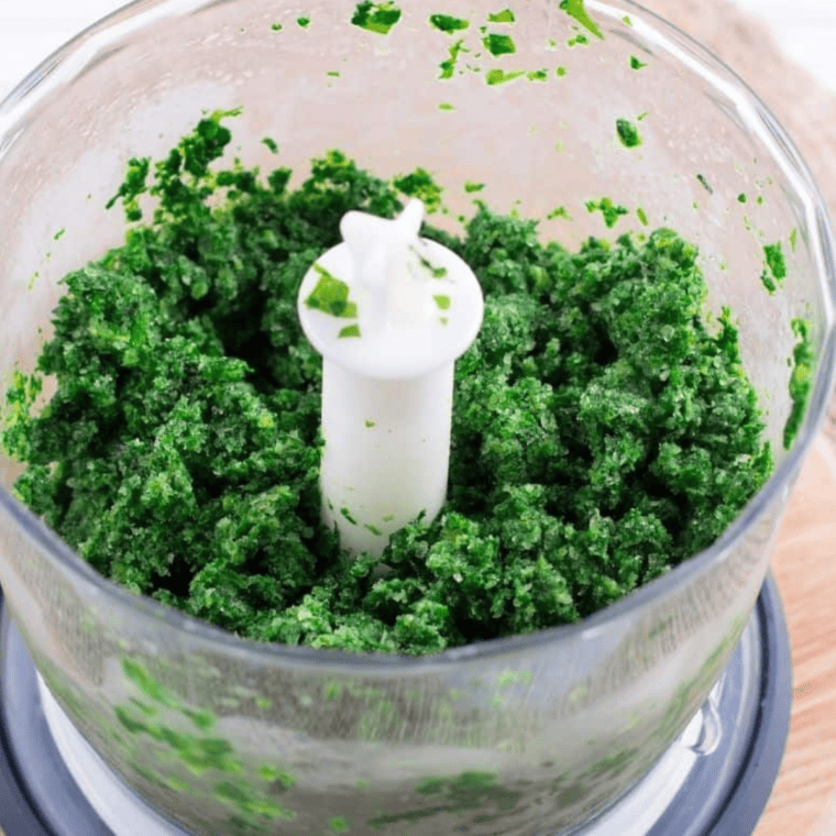 Minced garlic, grated lemon zest, chopped parsley, and herbs being mixed in a bowl.