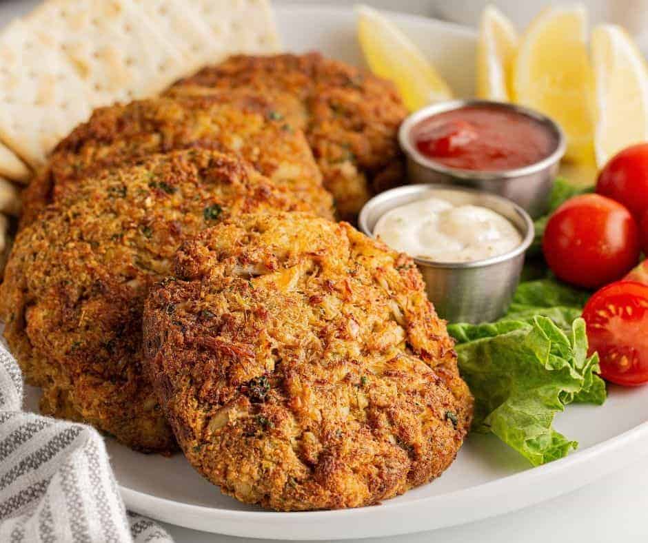 Golden brown Maryland-style crab cakes made in the air fryer, showcasing lump crab meat and served with a dipping sauce.