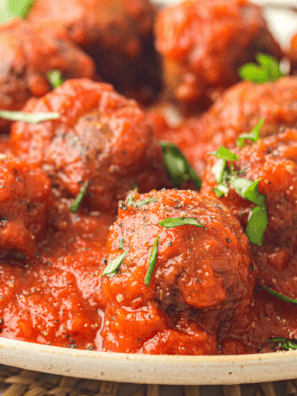 Olive Garden Meatballs served in marinara sauce, garnished with fresh herbs.