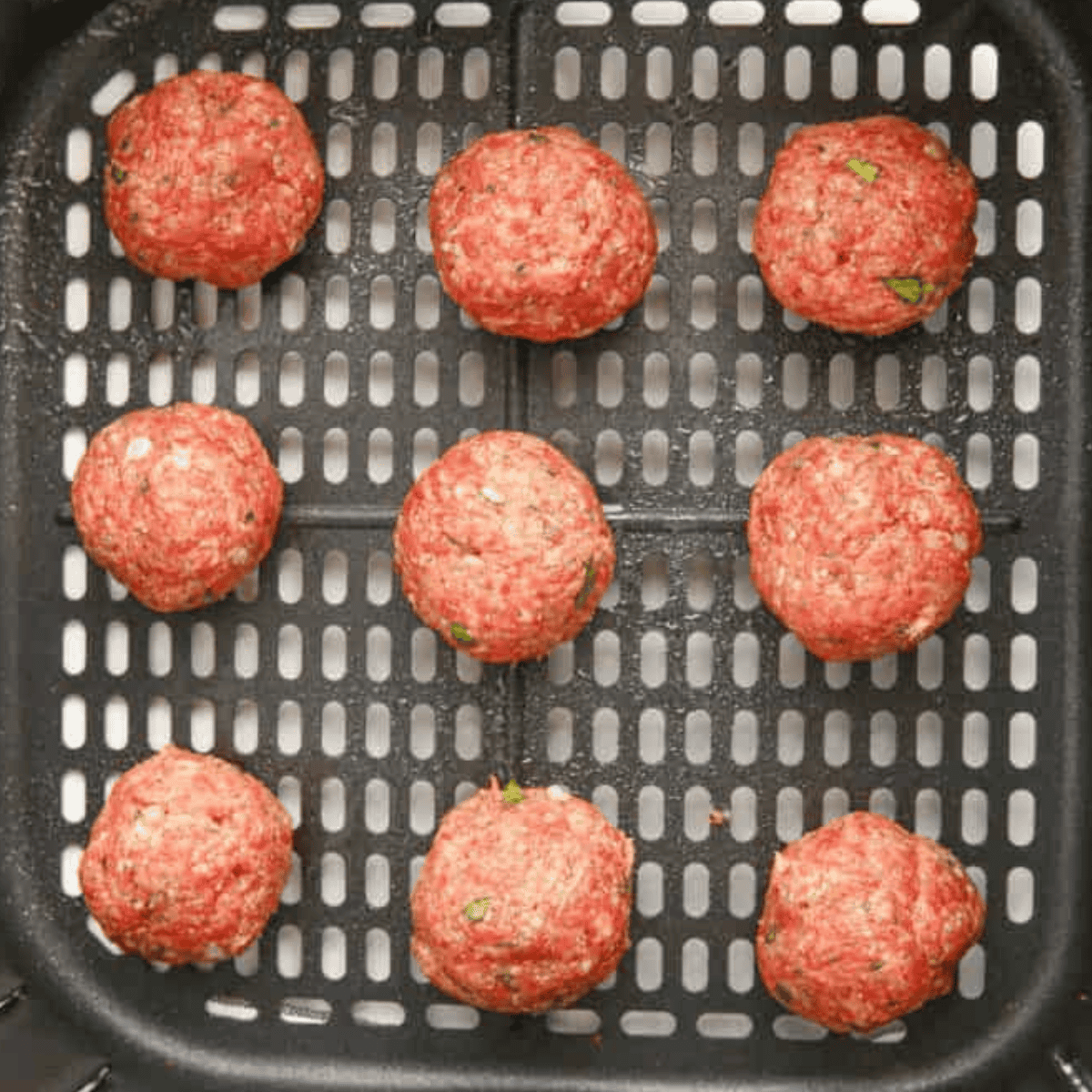 Single layer of Olive Garden Meatballs in the air fryer basket.