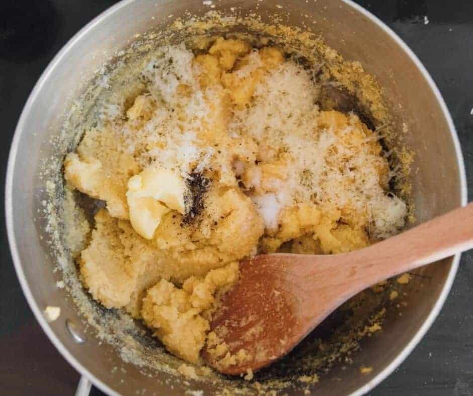 Stirring butter and parmesan into cooked polenta until smooth