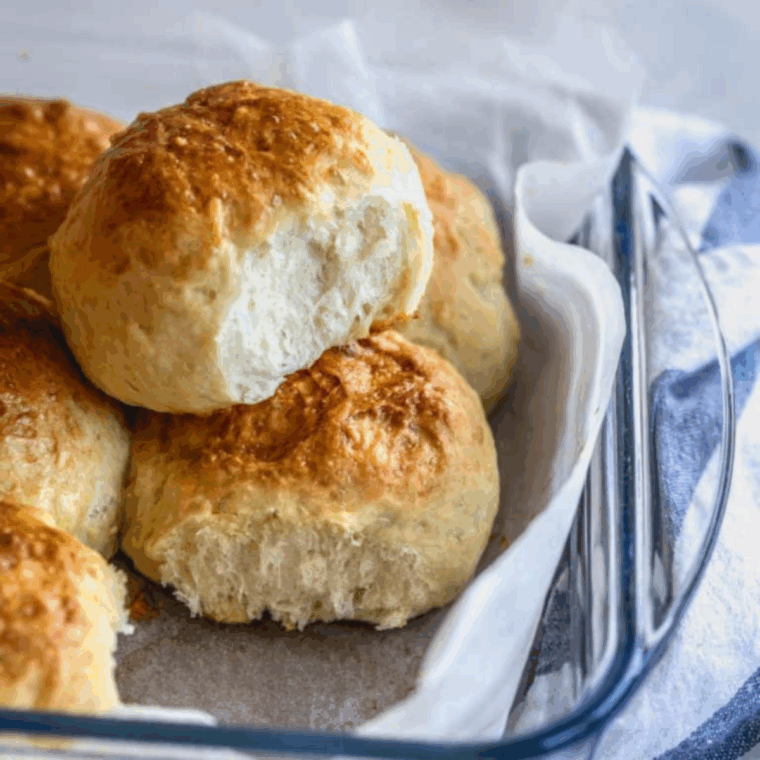Golden, fluffy sourdough discard dinner rolls freshly baked and served on a plate