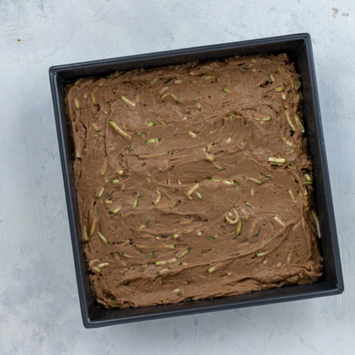 Pouring batter into an air fryer-safe pan: Brownie batter being poured into a greased, air fryer-safe baking pan.