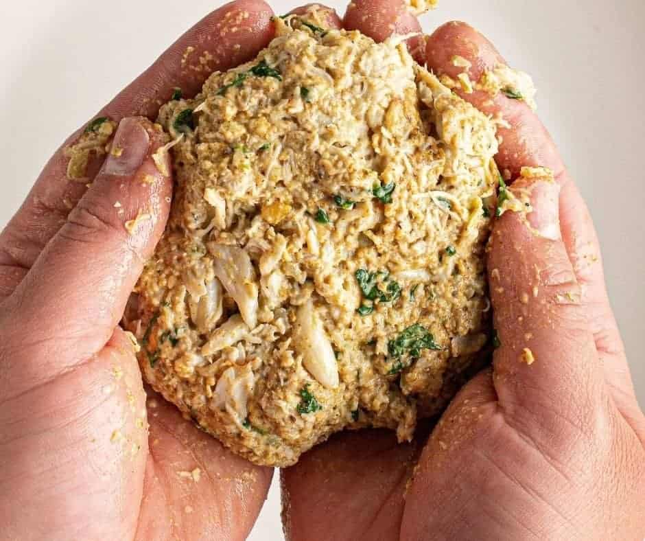 Shaping crab cake mixture into patties on a cutting board.