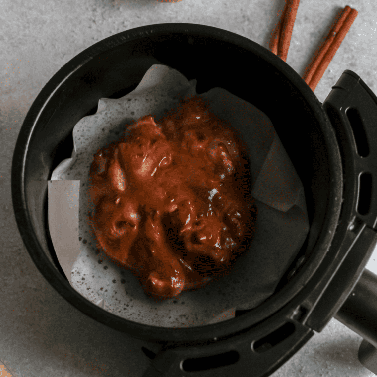 Spoonfuls of fritter batter shaped into rounds on air fryer parchment