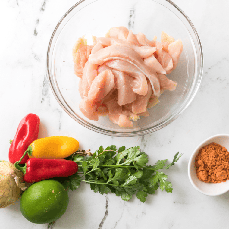 Sliced chicken, red and green bell peppers, onion, lime, and fajita seasoning
