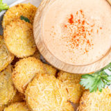Crispy air fryer fried squash rounds with golden cornmeal breading stacked on a white plate