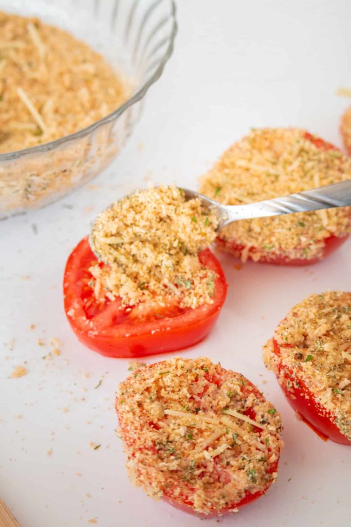 closeup: adding topping to air fryer parmesan tomatoes before roasting