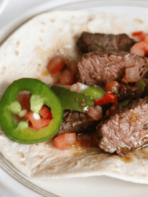 Air fryer steak fajitas with charred peppers and onions piled on a warm flour tortilla