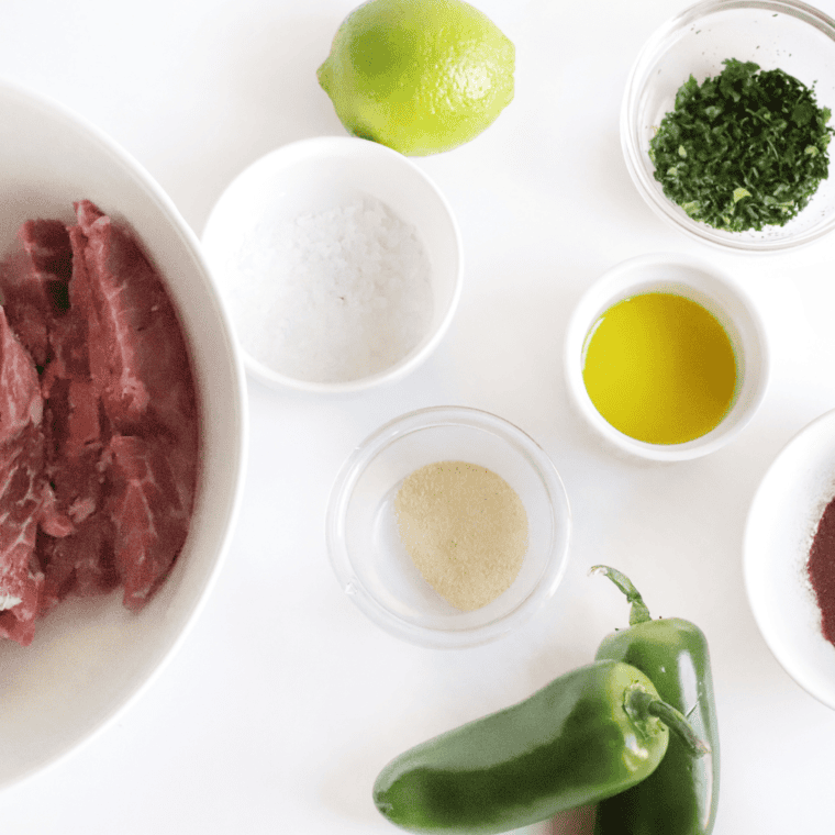 Ingredients for Air Fryer Steak Fajitas including flank steak, bell peppers, onion, jalapeño, lime, cilantro, and cumin