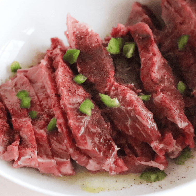 Flank steak being sliced into thin strips against the grain for Air Fryer Steak Fajitas