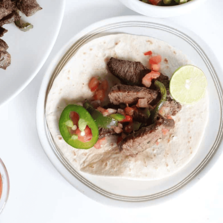Cooked Air Fryer Steak Fajitas piled onto a warm tortilla with toppings