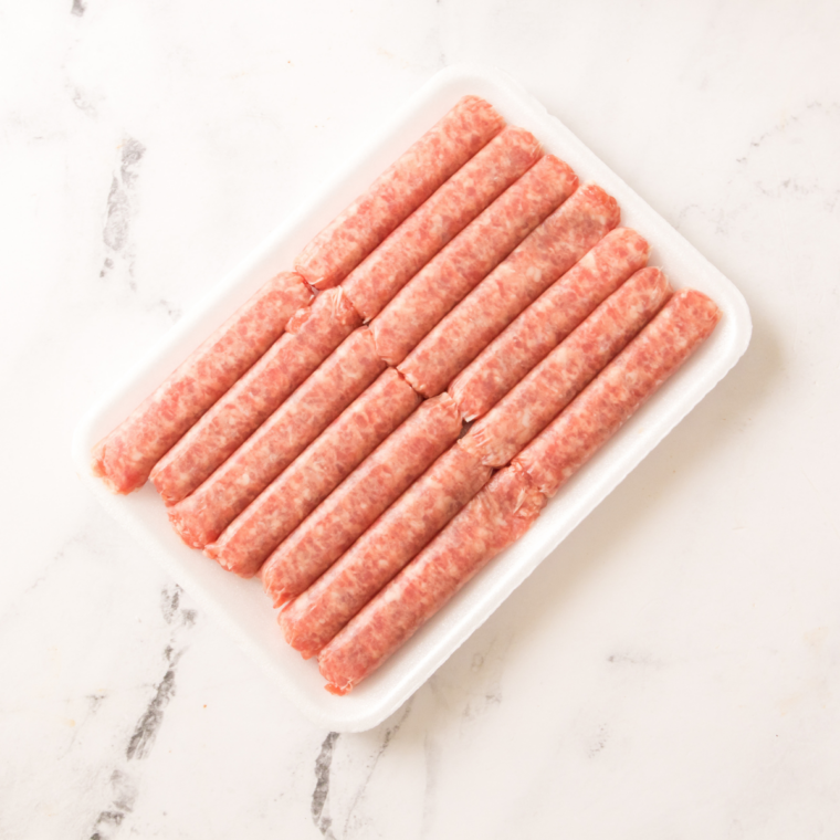 Ninja Crispi PowerPod, glass container, crisper plate, and raw breakfast sausage links laid out on a counter