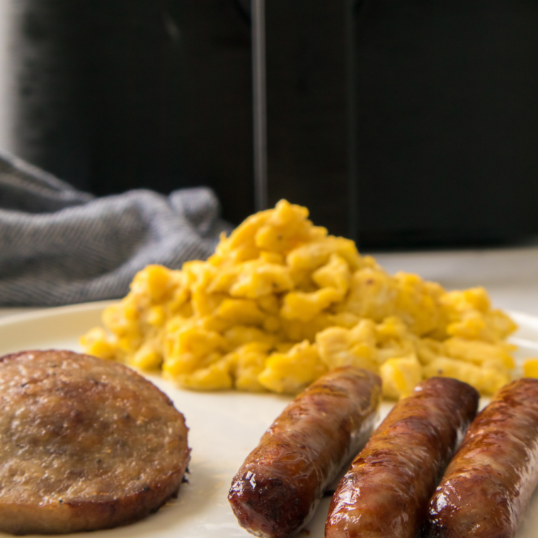 Sausage and egg breakfast sandwich served with fresh fruit on a plate