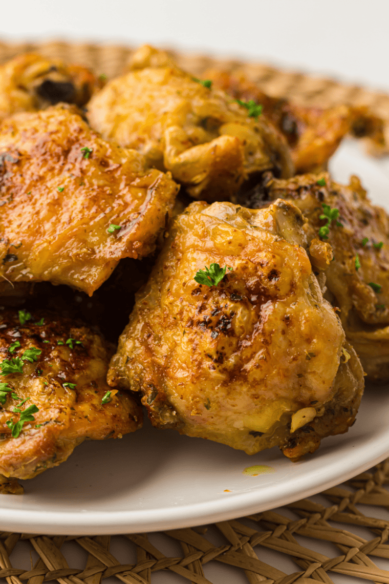 Crispy golden-brown chicken thighs fresh from a Ninja Crispi air fryer, garnished with herbs on a serving plate.
