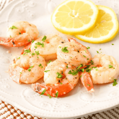 "Air fryer garlic butter shrimp garnished with parsley and lemon wedges"