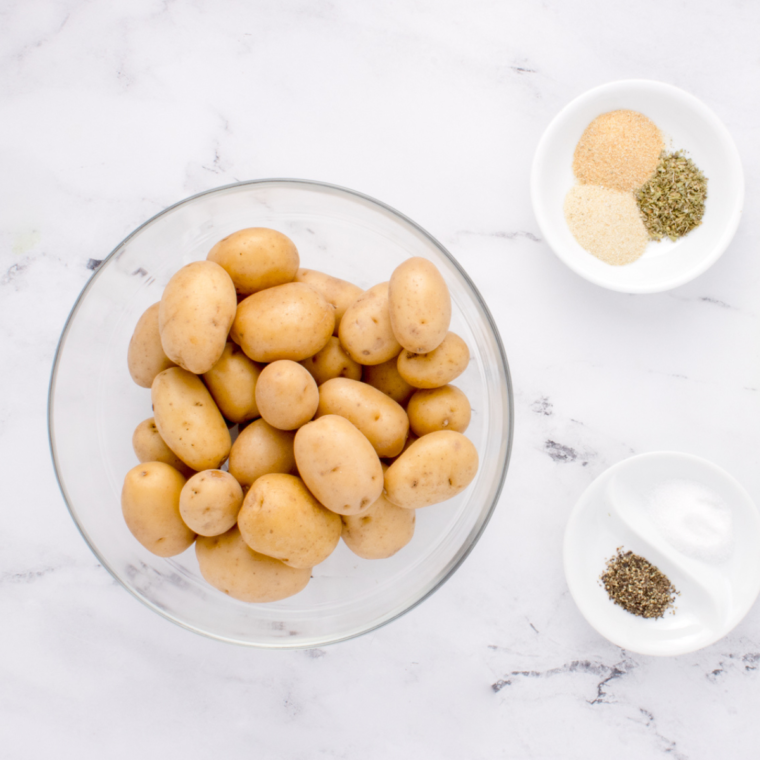 Yukon Gold potatoes, olive oil, fresh rosemary, salt, and pepper laid out on a counter