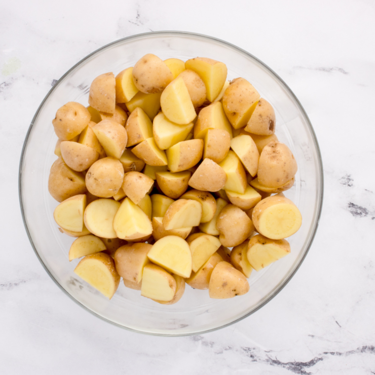 Diced potatoes tossed with olive oil and chopped rosemary in a mixing bowl