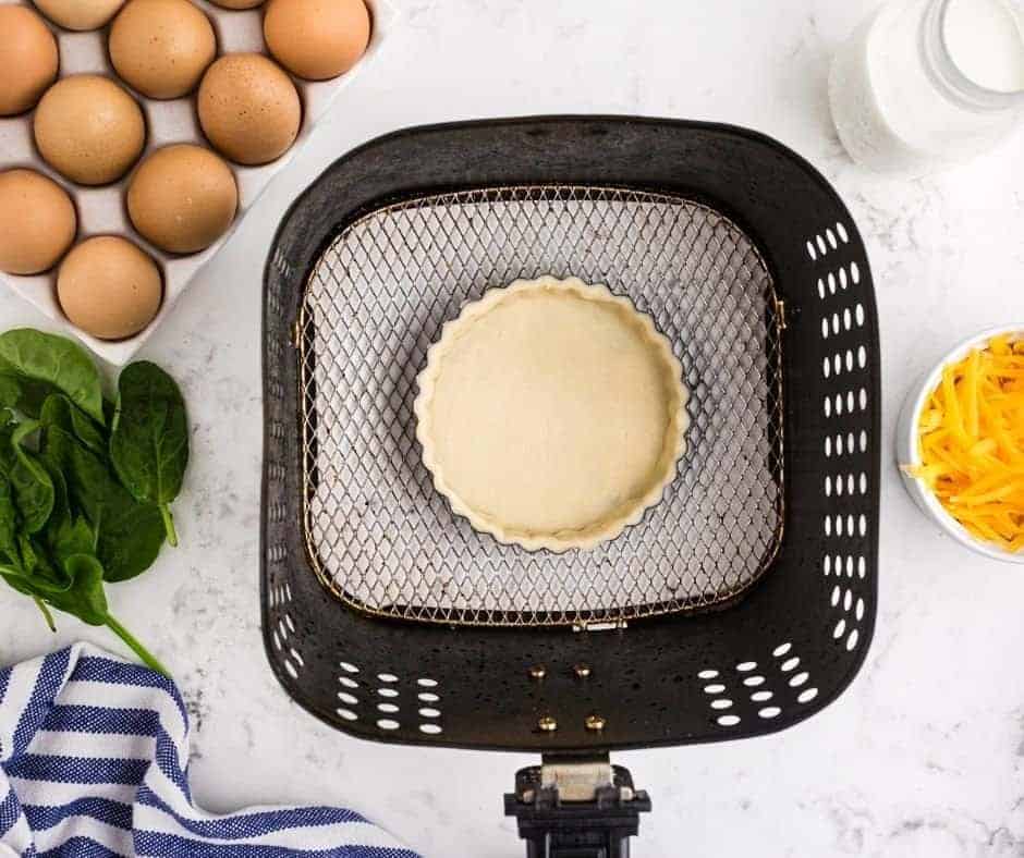 Placing the pie crust into the air fryer, and blind baking.