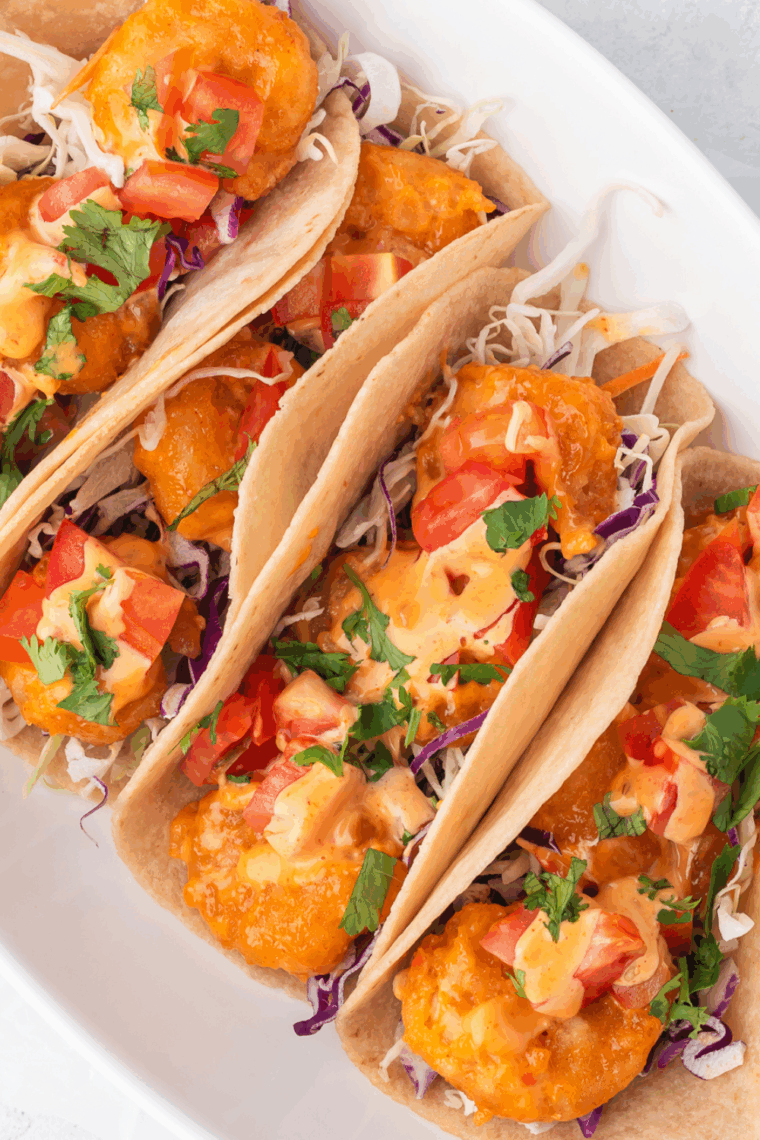 Close-up of taco-seasoned shrimp piled in a warm corn tortilla with avocado slices