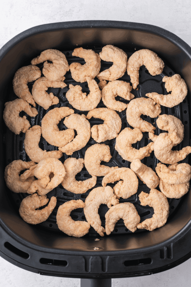 Seasoned shrimp arranged in a single layer in an air fryer basket