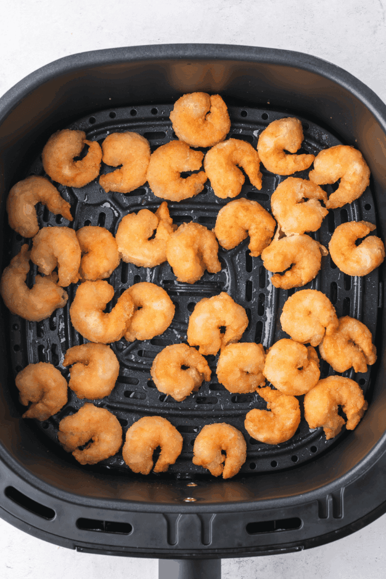 Cooked shrimp being added to warm tortillas with shredded cabbage