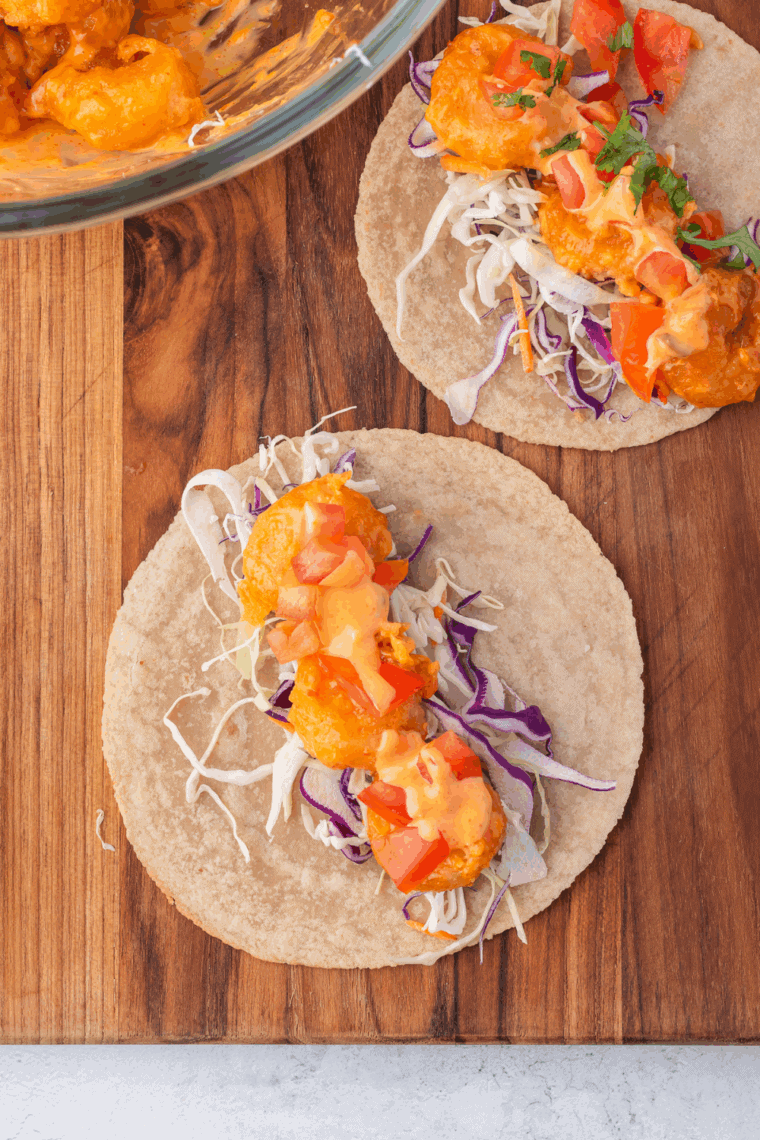 Close-up of crispy taco-seasoned shrimp in a corn tortilla with avocado slices
